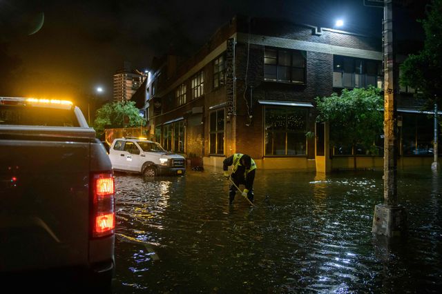 A worker unblocks drains on a street affected by floodwater in Greenpoint early on September 2nd, 2021, as flash flooding and record-breaking rainfall brought by the remnants of Storm Ida swept through Brooklyn.